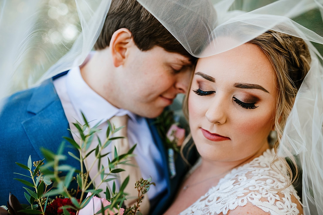 bride and groom snuggling during wedding portraits under veil at Cypress Hall in Hernando, MS