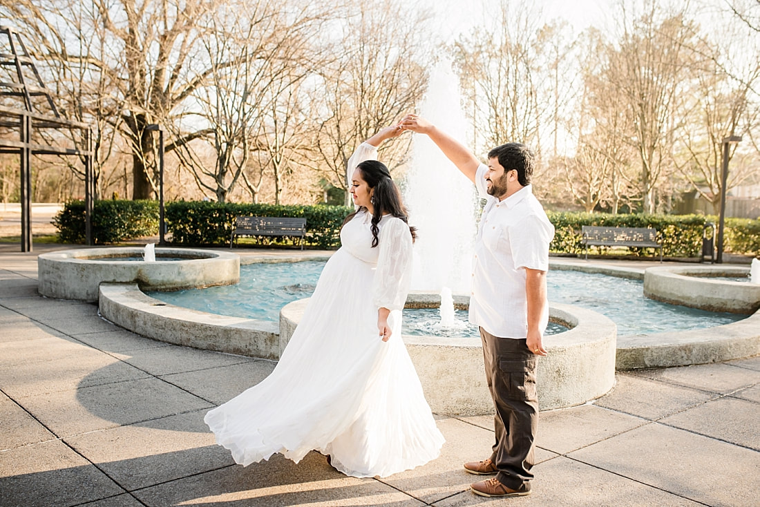 father and mother dancing by the fountain during maternity photo session at memphis botanic garden