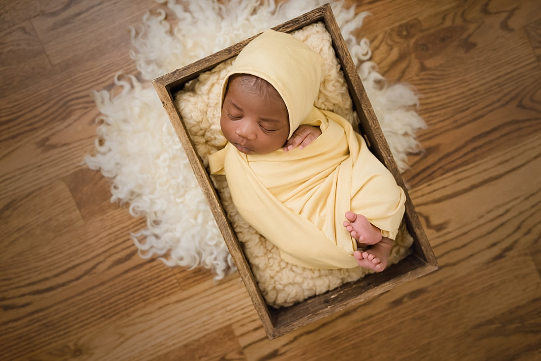 baby wrapped in yellow and sleeping in wooden box for newborn photos in Collierville, TN