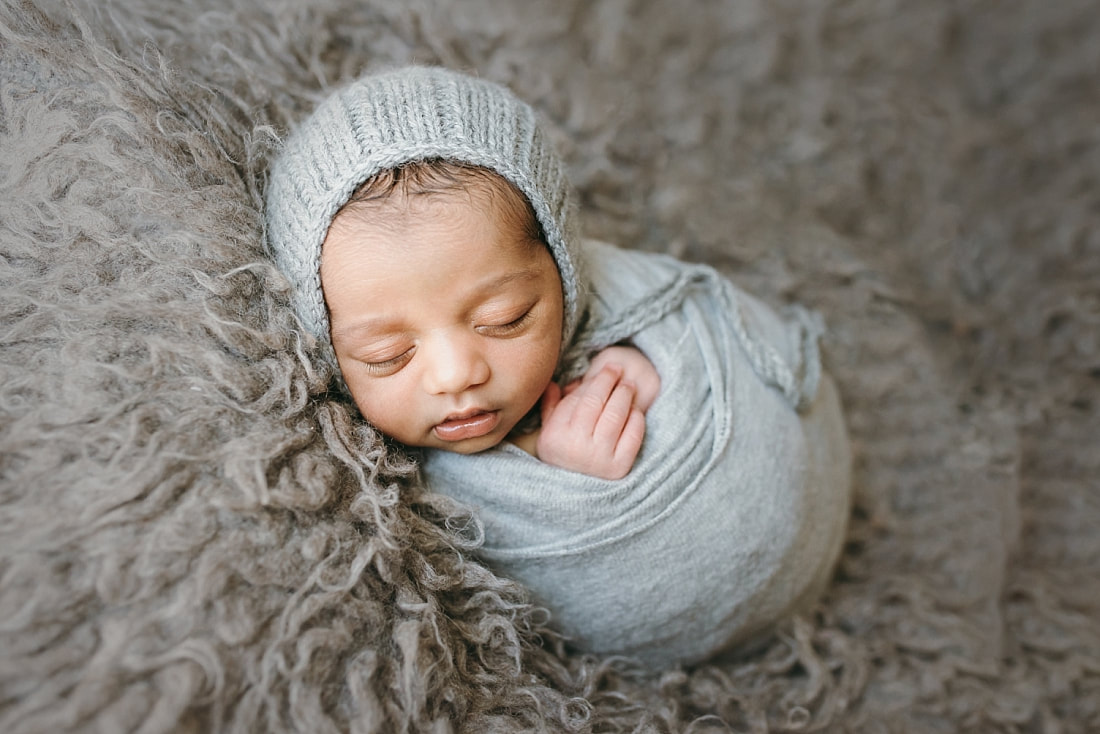 newborn baby boy wearing knit bonnet and swaddled in soft blanket during newborn session in memphis tn