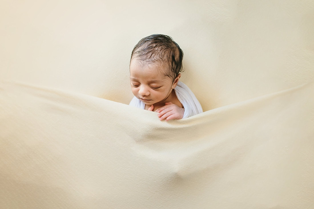 newborn baby wrapped in white on yellow background for newborn photos in memphis